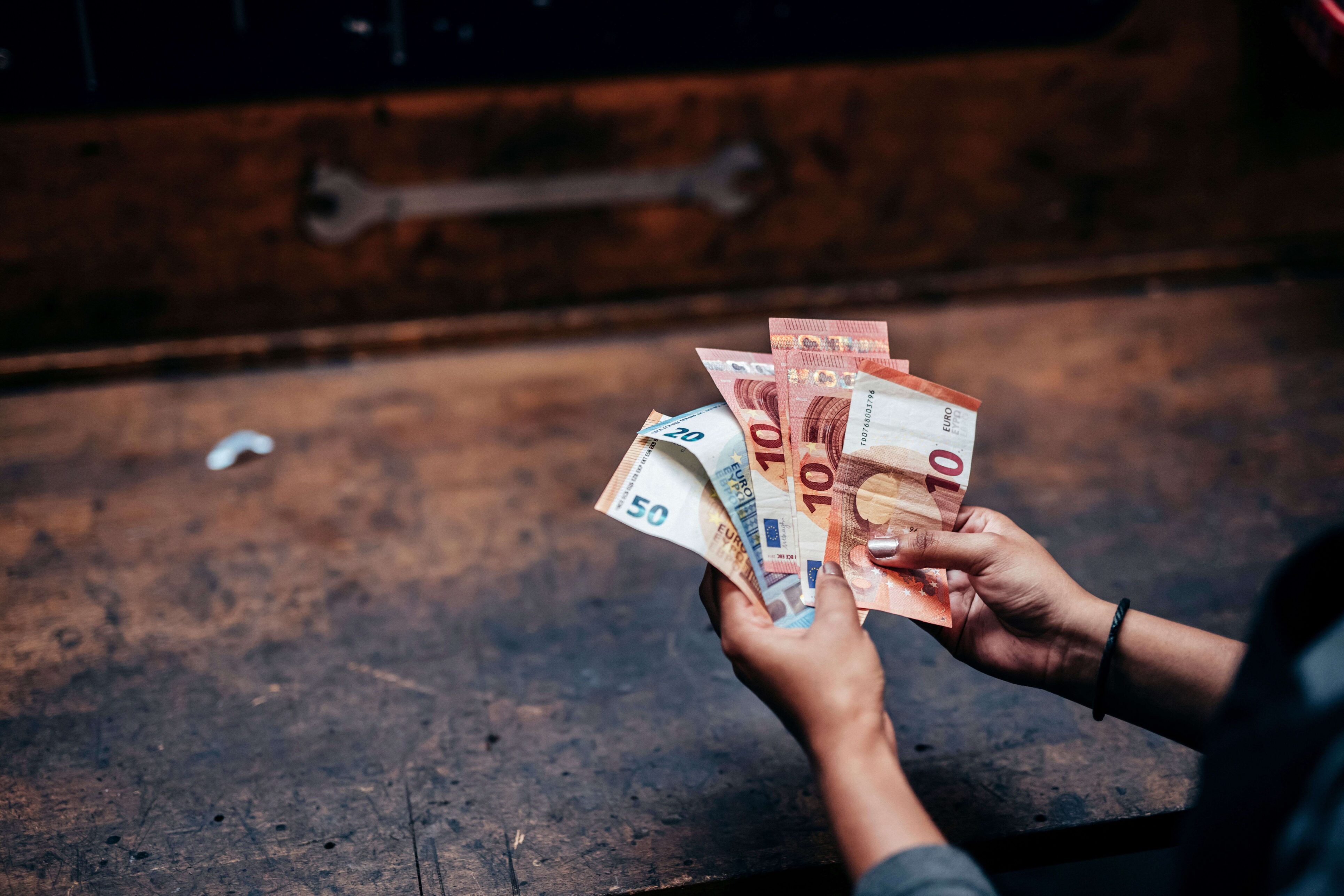 Eine Person hält 50-, 20- und 10-Euro-Scheine aufgefächert in beiden Händen.