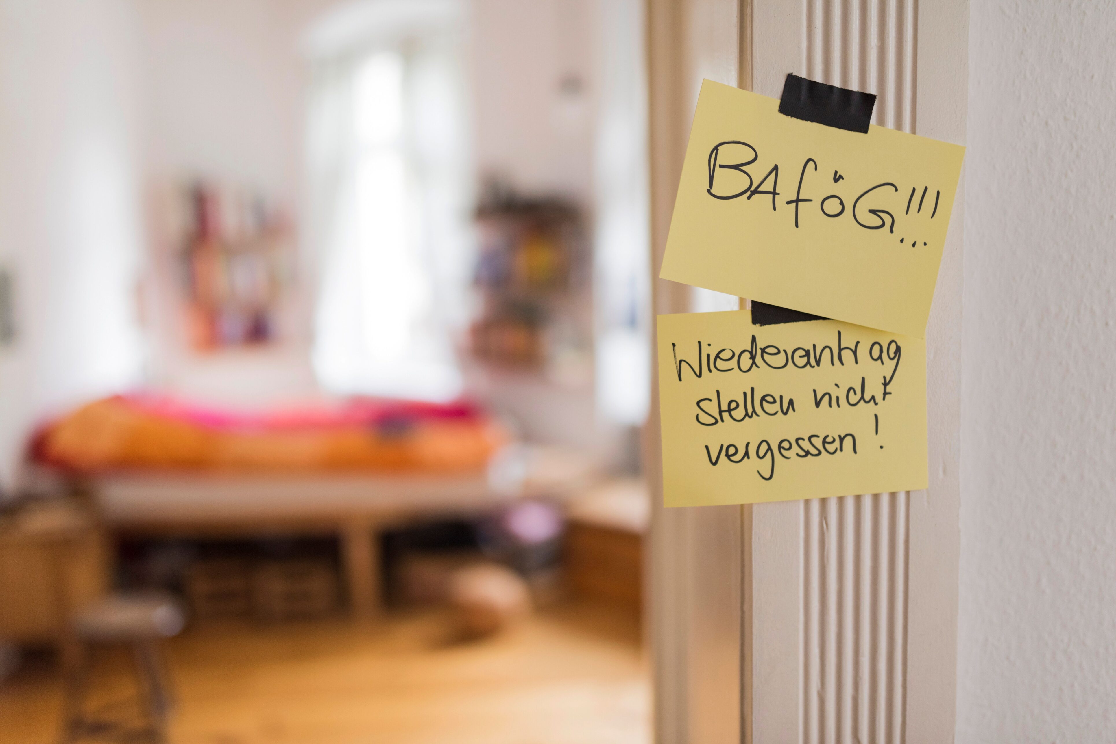 An der Seite eines Türrahmens hängen zwei Post-Its mit der Aufschrift "BAföG!!!" und "Wiederantrag stellen nicht vergessen!"