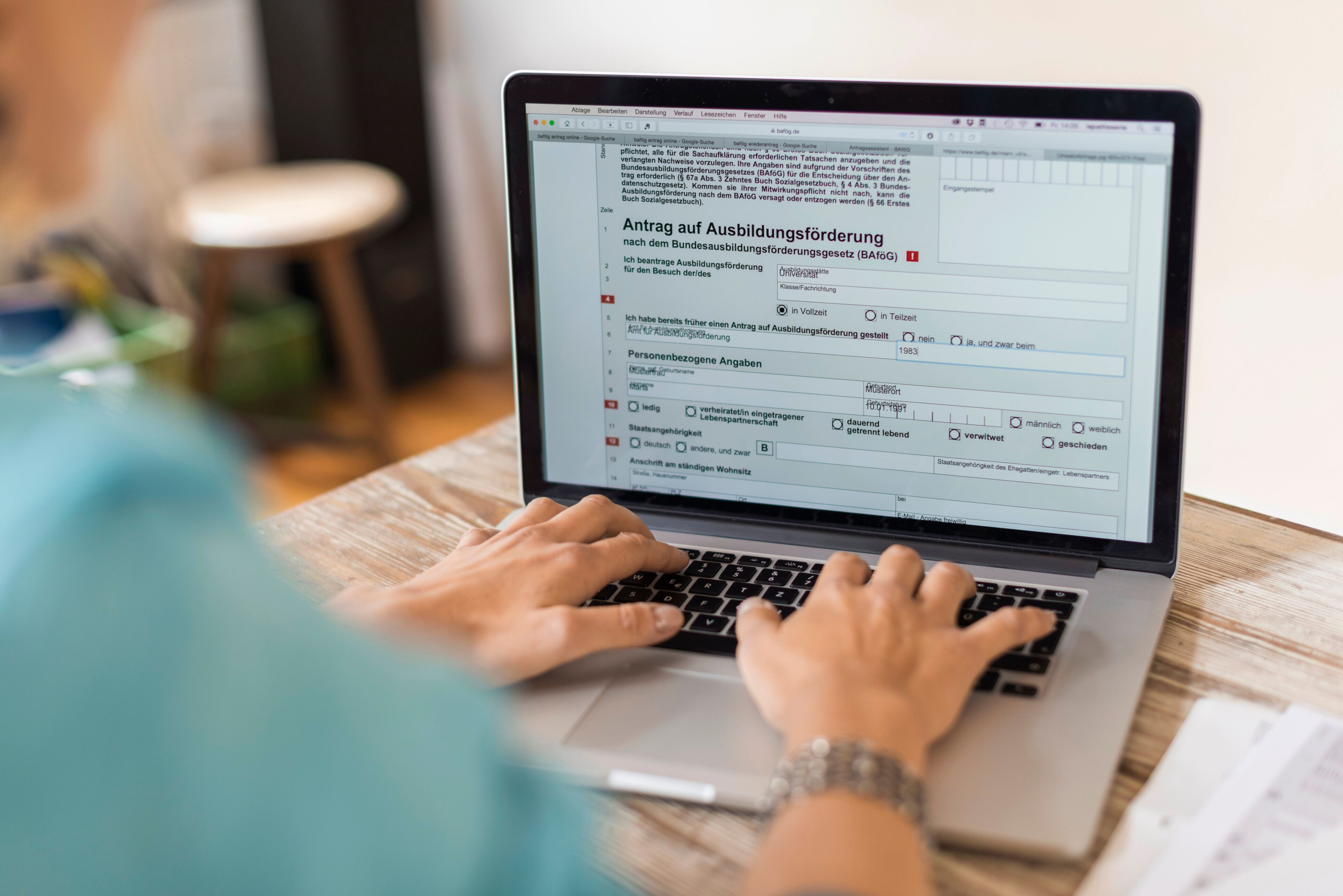Eine Person sitzt vor ihrem Laptop und füllt daran den Antrag auf Ausbildungsförderung aus.