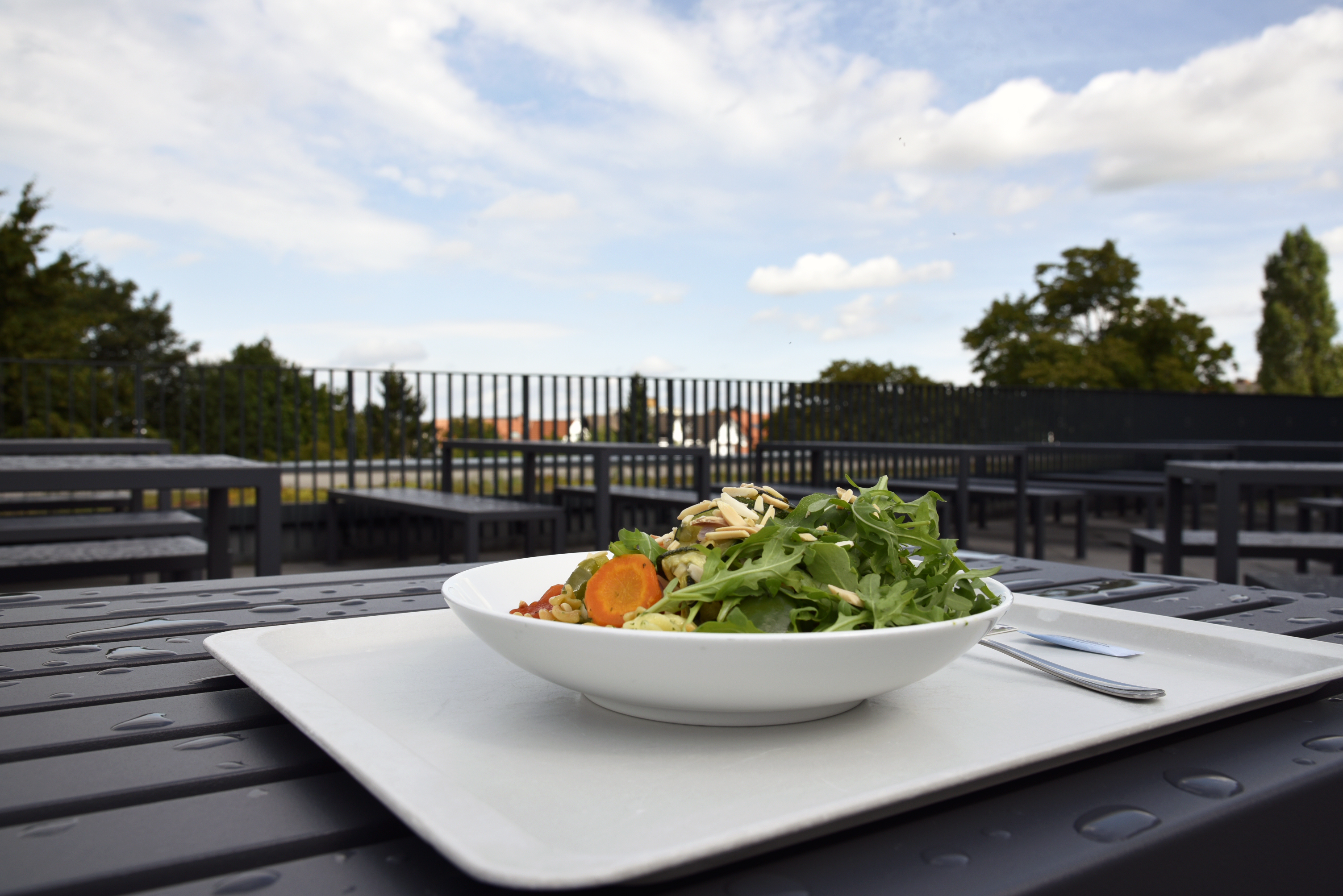 Auf der Außenterrasse einer Mensa steht auf einem Tisch ein Tablett mit einem Mittagsgericht