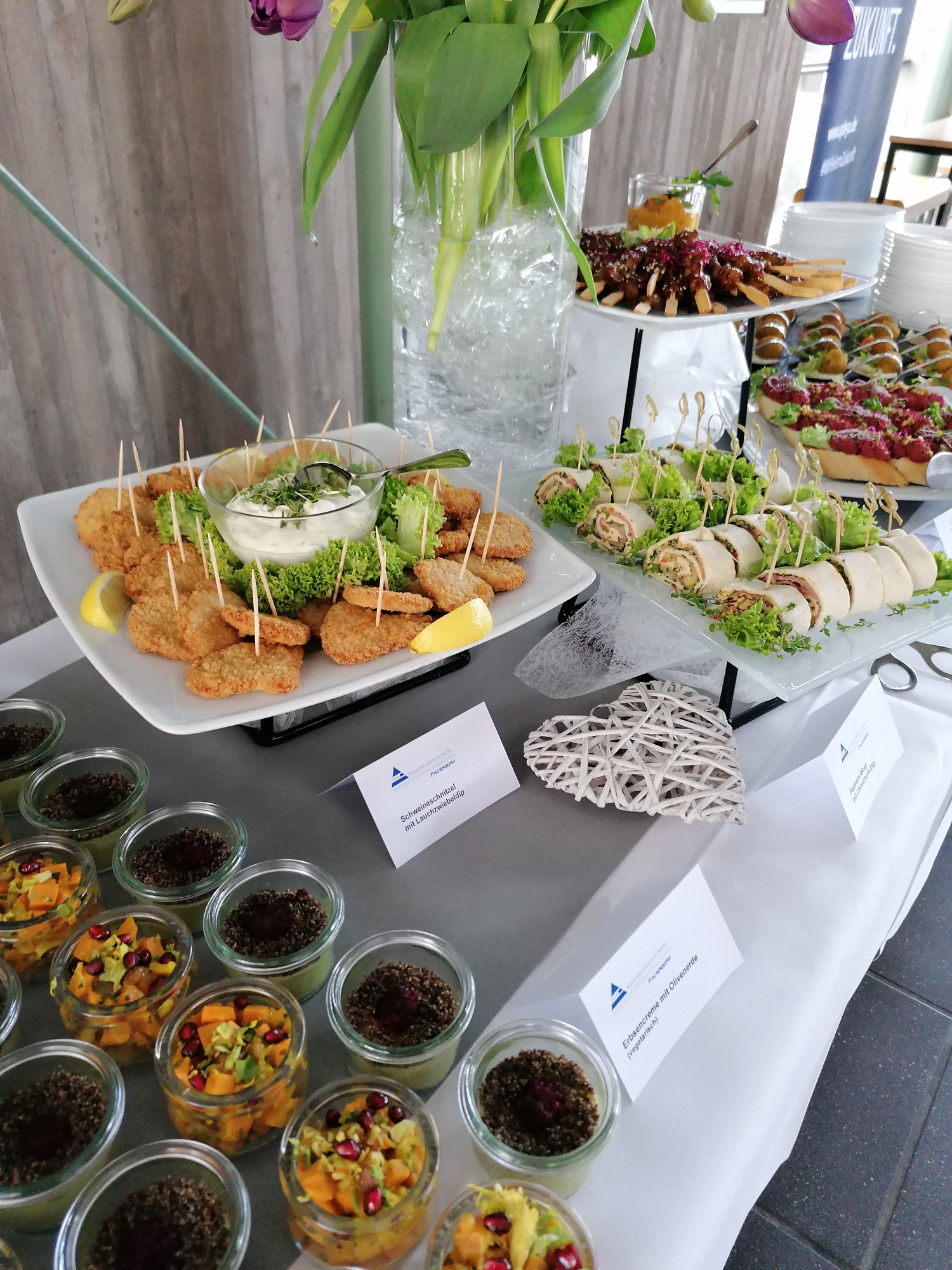 Ausschnitt eines Buffets mit verschiedenen Speisen in Gläsern oder auf Tellern angerichtet, z.B. Wraps, Schnitzel