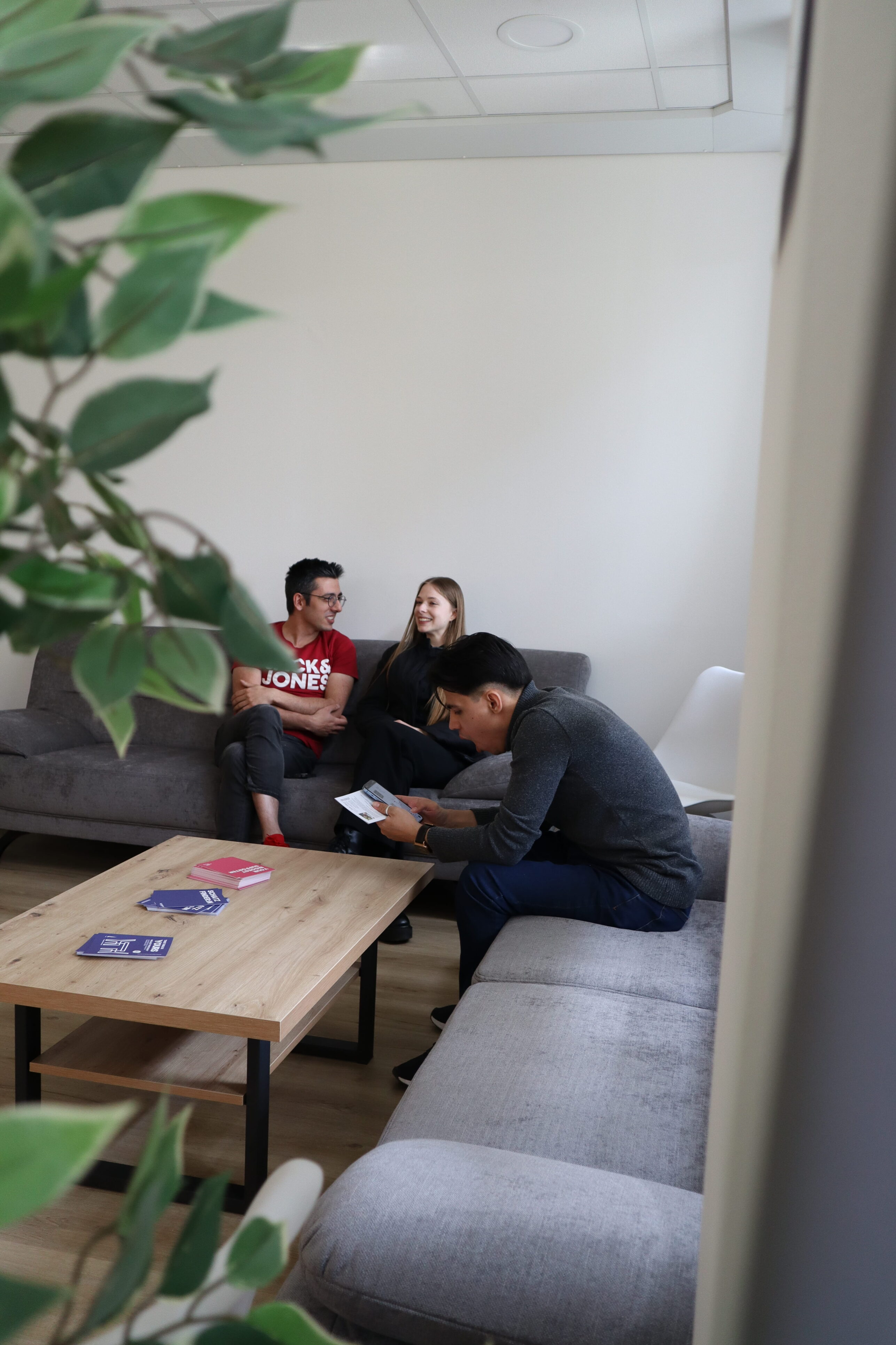 Three people sit in a corner on two modern sofa sets