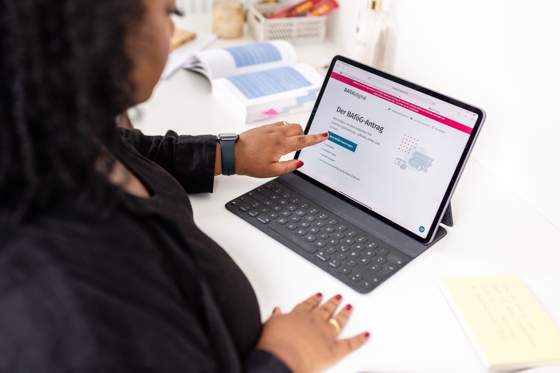 Eine Person nutzt ein Tablet, um den BAföG-Antrag online auszufüllen. Auf dem Bildschirm sind Informationen zu sehen.