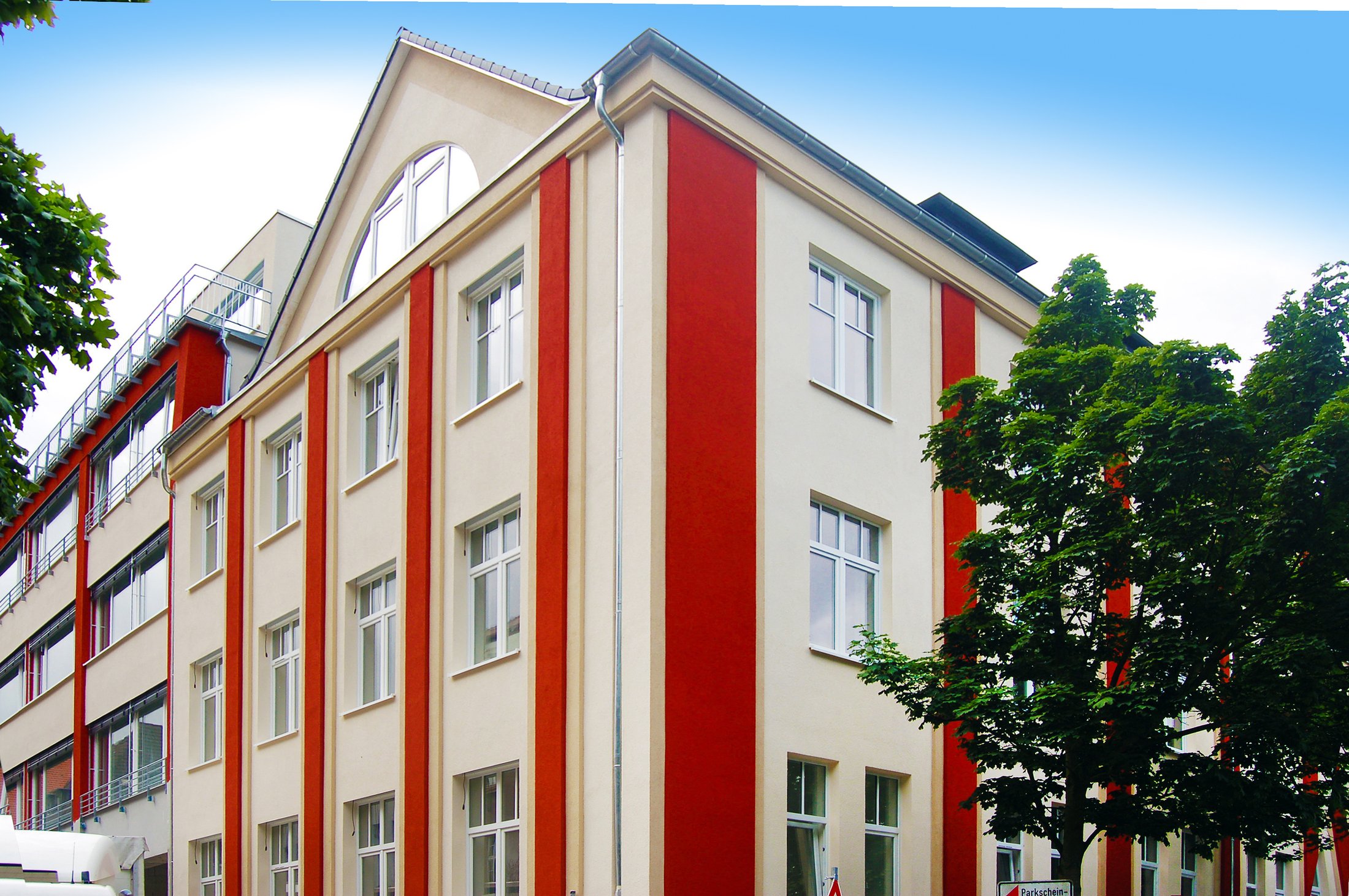 Studierendenwohnheim in Hamm: modernes Gebäude mit roten und weißen Fassadenelementen und großen Fenstern.