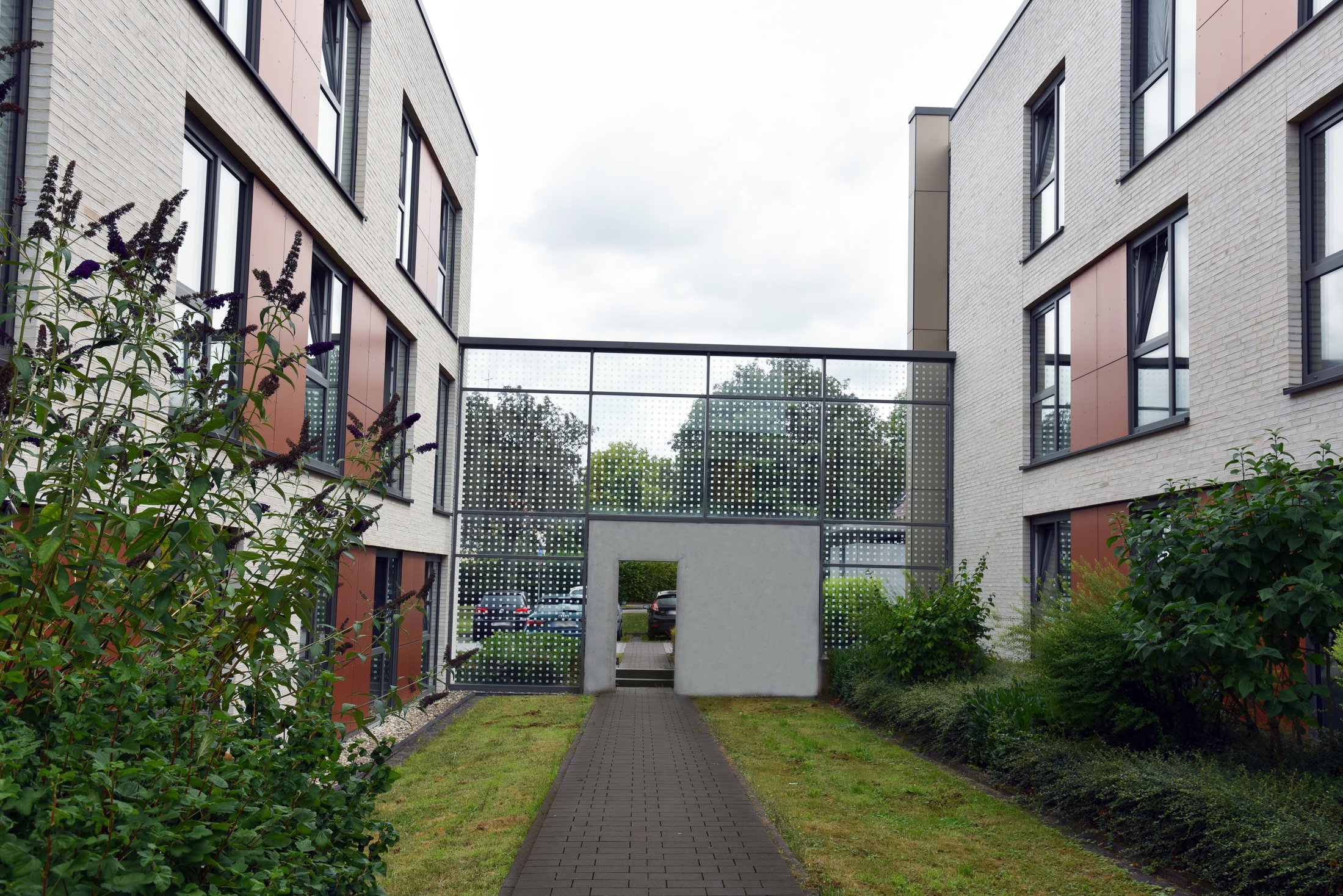 Studierendenwohnheim Paderborn - Alois Fuchs Weg, moderne Architektur mit grünem Eingangsbereich und Verbindungsbau.