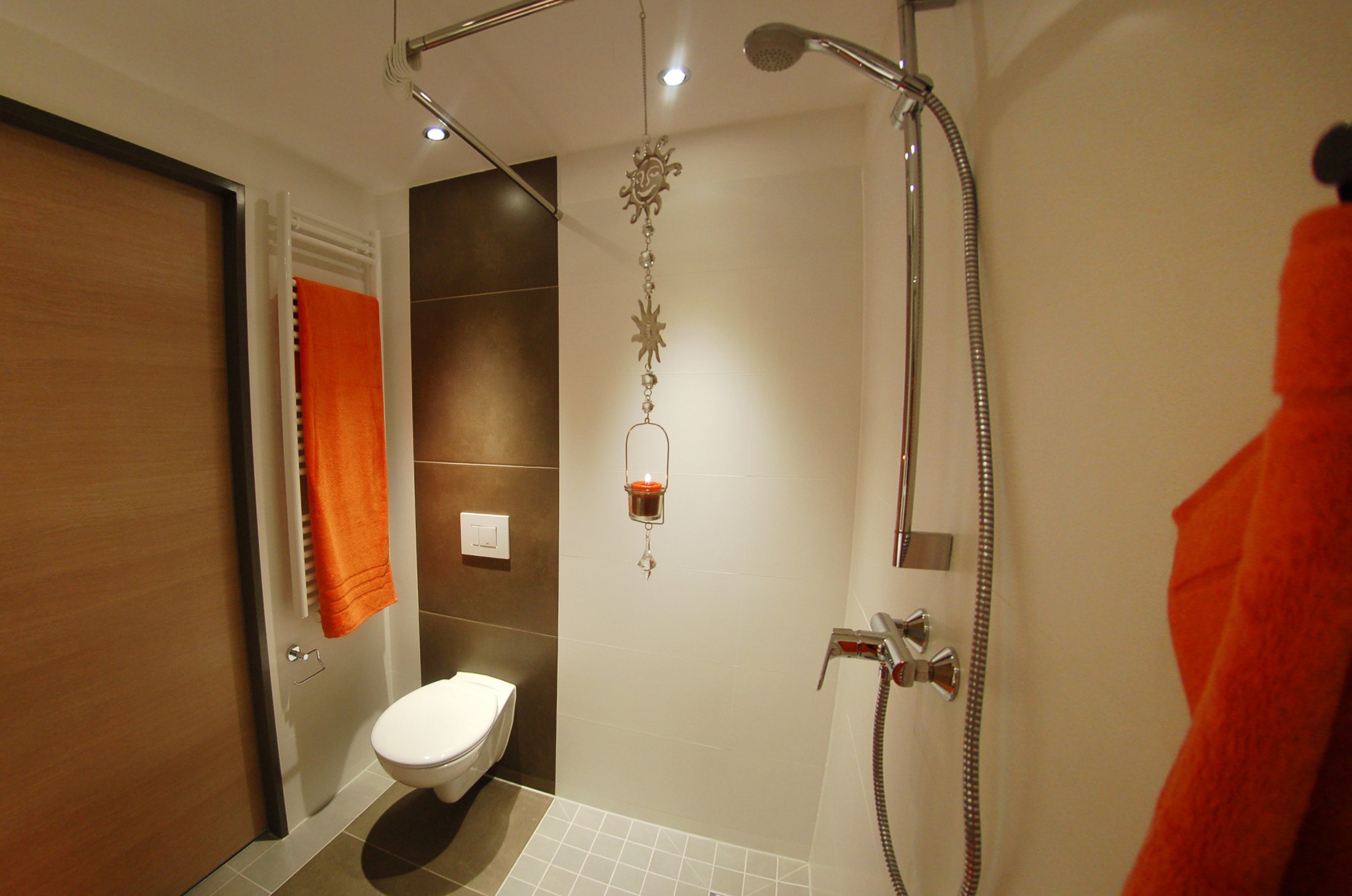 Badezimmer im Studierendenwohnheim Paderborn - Alois Fuchs Weg mit Dusche, WC und orangefarbenem Handtuch.