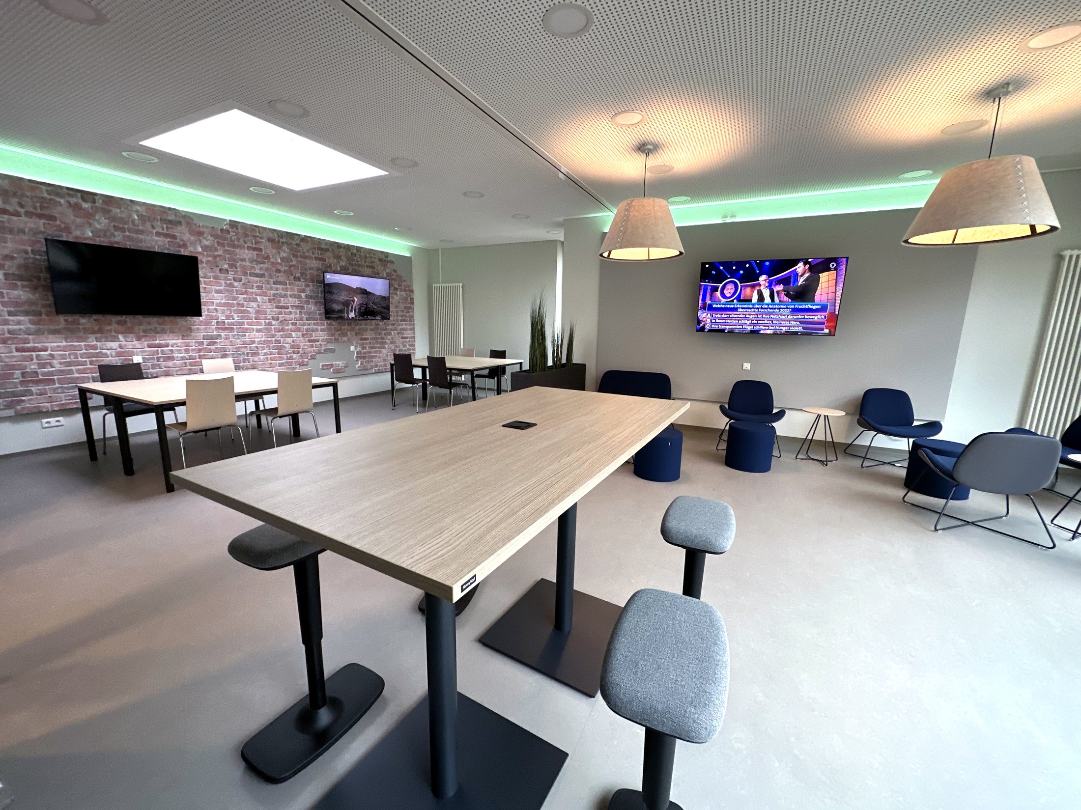 Modern communal area in Paderborn student hall of residence - Alois Fuchs Weg study room with tables and screens.