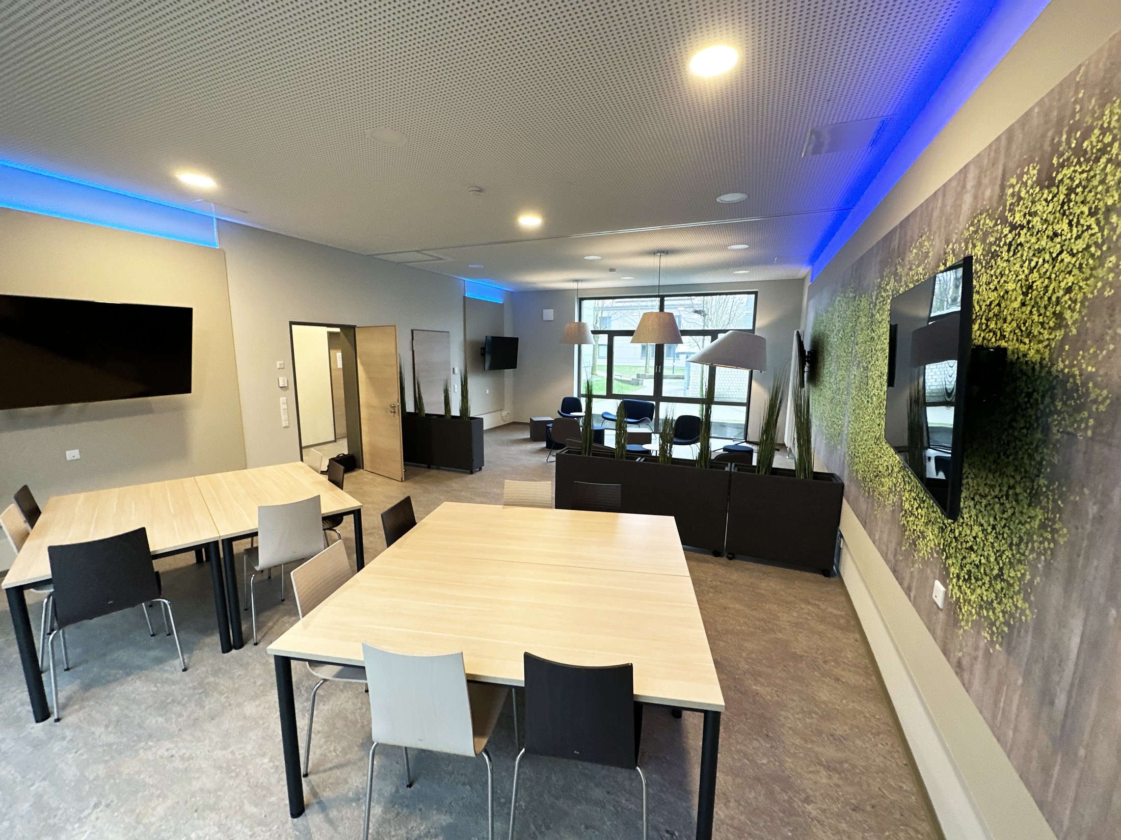 Modernes Gemeinschaftszimmer im Studierendenwohnheim Paderborn-Lernraum_Vogeliusweg mit Tischen und bequemen Sitzen.