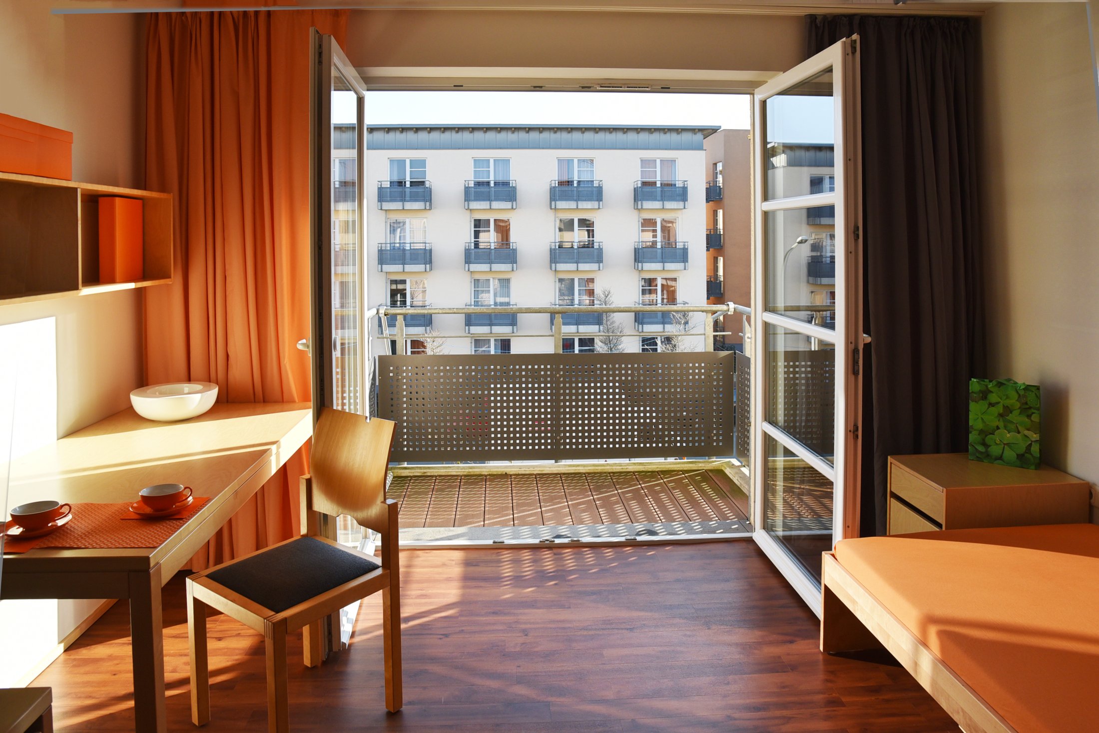 Hell erleuchtetes Zimmer im Studierendenwohnheim Paderborn-Mersinweg_4 mit Balkon, Tisch und Stuhl.