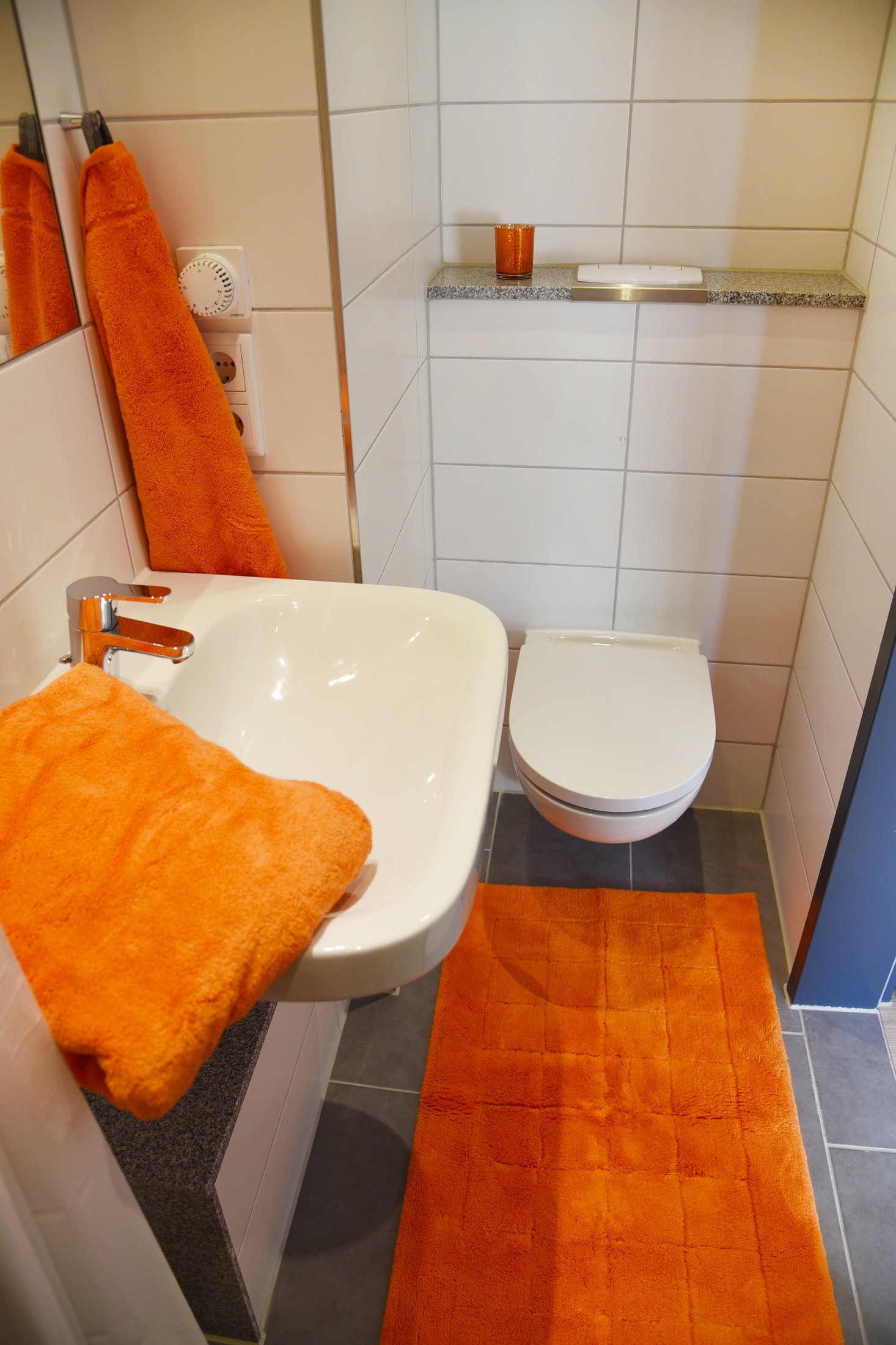 Bathroom in the Paderborn-Peter_Hille_Weg_11 student residence with light-coloured tiles and orange towels.