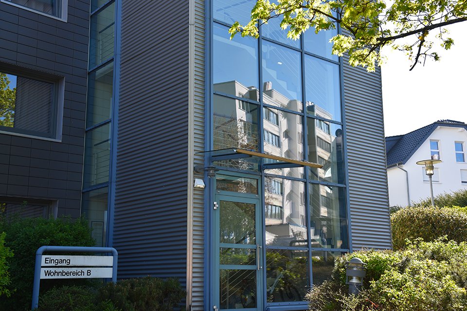 Eingang des Studierendenwohnheims am Peter-Hille-Weg 13 in Paderborn, moderne Fassade mit Fensterfront.