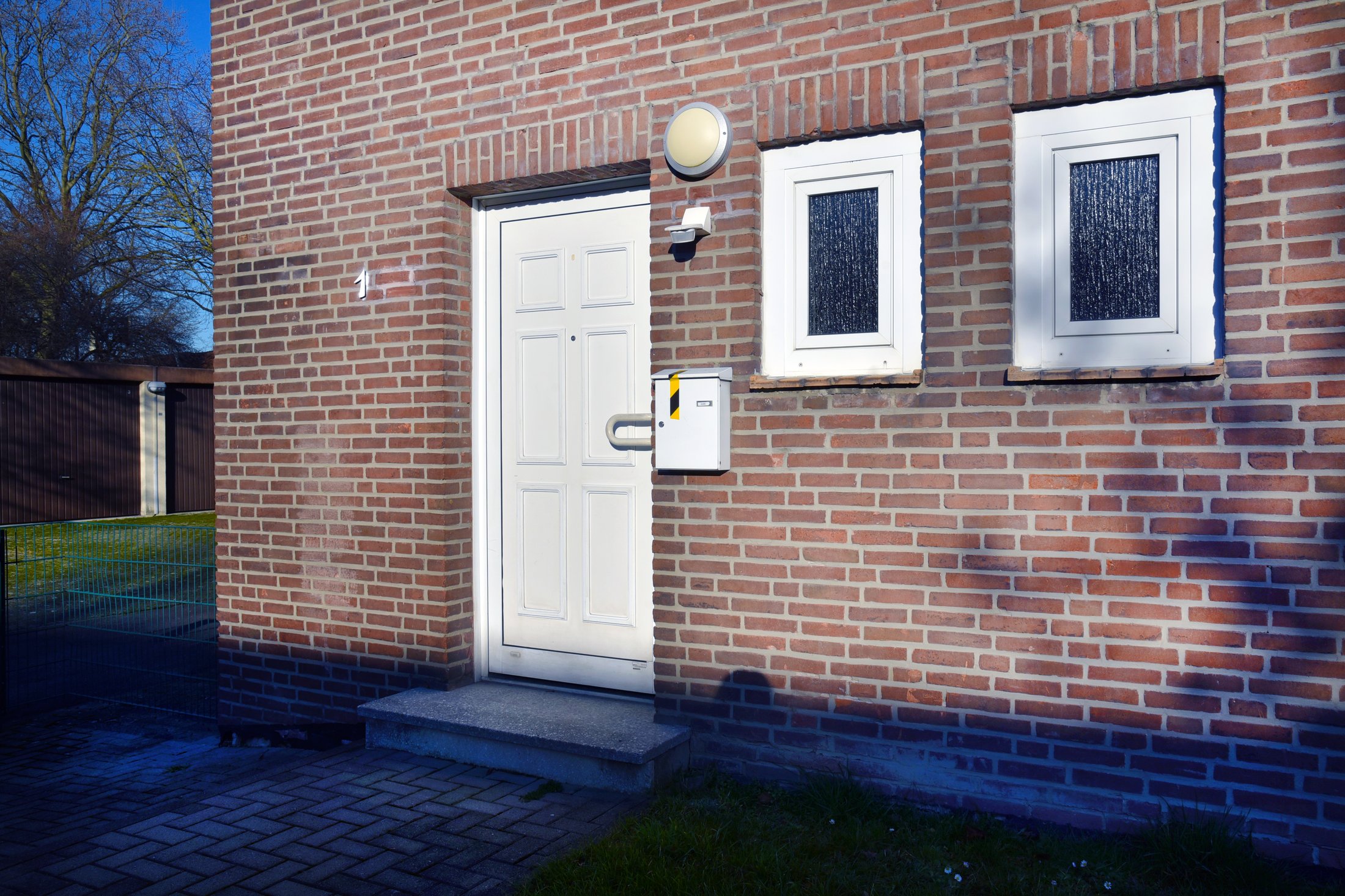 Eingang zu einem Studierendenwohnheim in Paderborn-Uhlandstraße mit einer weißen Tür und zwei Fenstern.