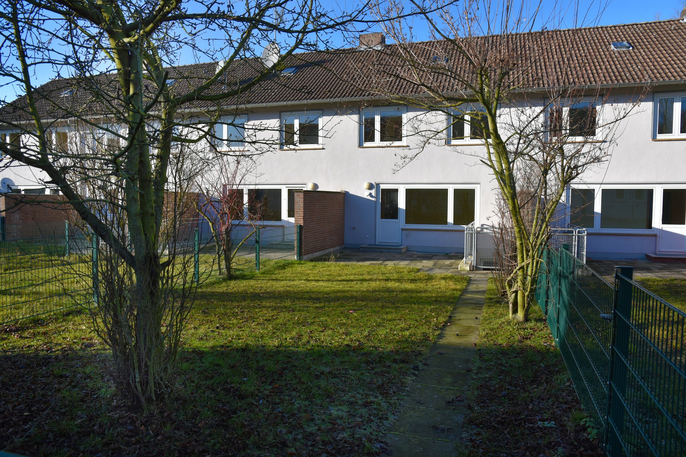 Studierendenwohnheim in Paderborn-Uhlandstraße, mit Garten, Bäumen und modernen Fenstern im Hintergrund.
